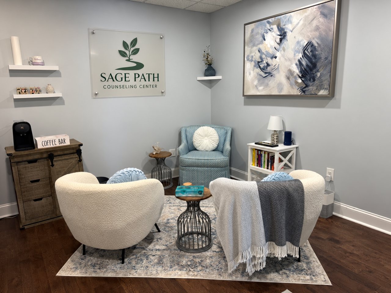 The Sage Path waiting room: armchairs, blankets, a bookshelf and a coffee bar